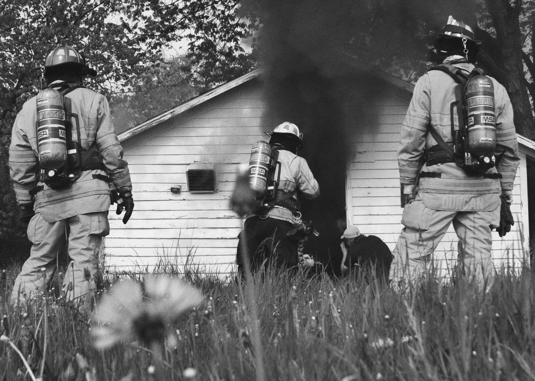 Fire engine parked beside a smoke-damaged vacant building along a rural highway